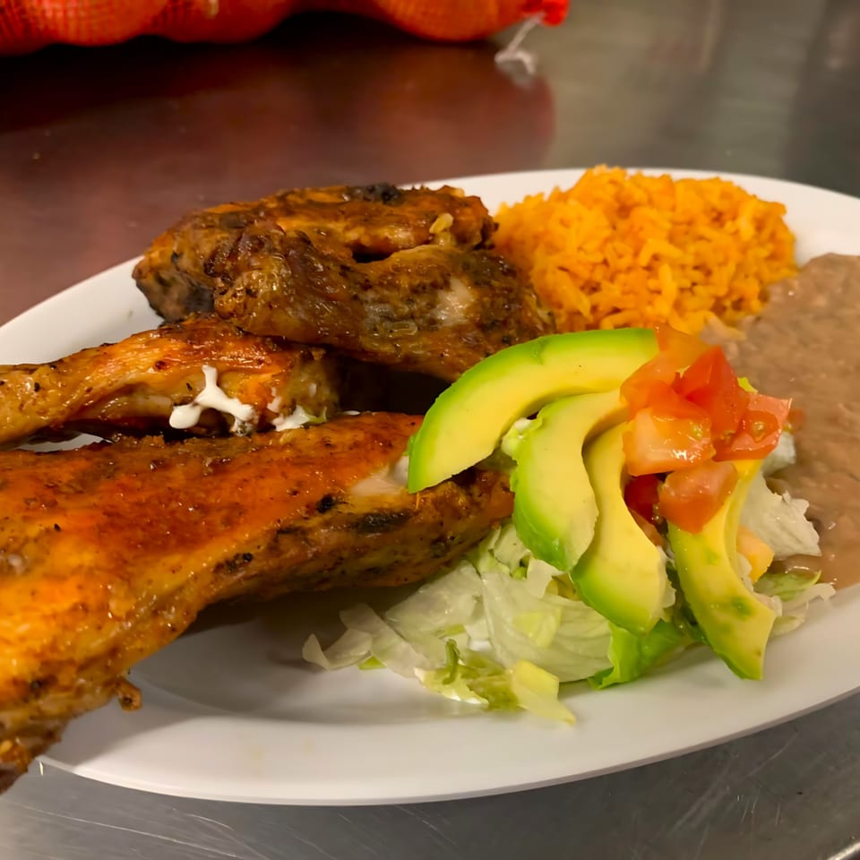 Cocina Doña Chuyita's Mexican grilled chicken with rice, refried beans, avocado, and salad.